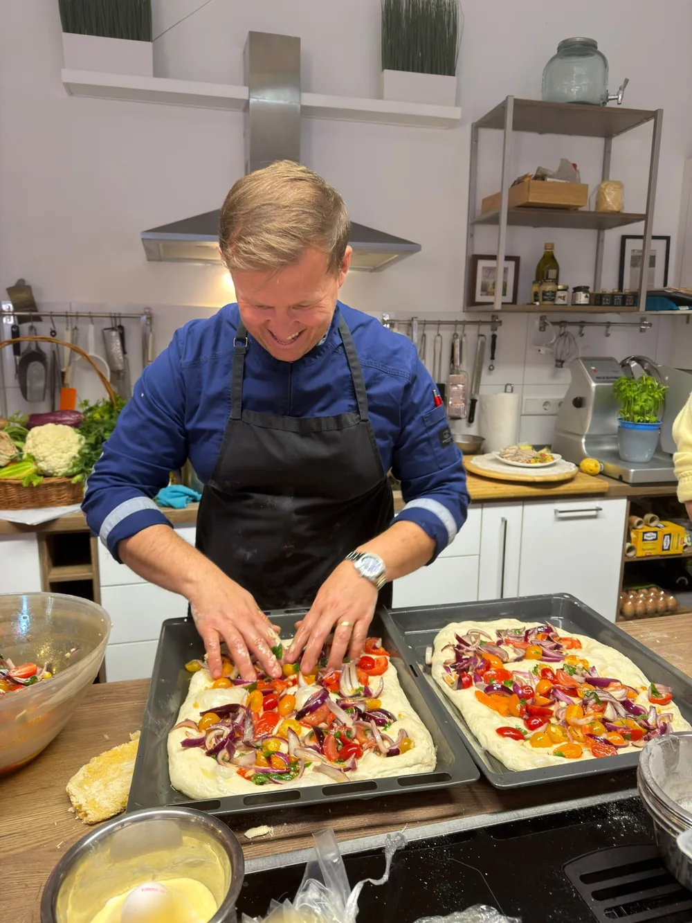 Küchenchef Ervin Trungu belegt Focaccia mit Tomaten und roten Zwiebeln